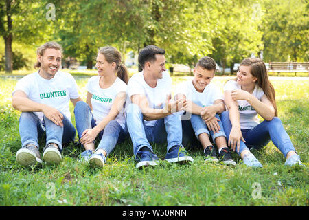 Gruppo di volontari seduti sul prato verde all'aperto Foto Stock