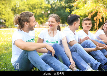 Gruppo di volontari seduti sul prato verde all'aperto Foto Stock