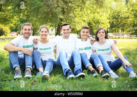 Gruppo di volontari seduti sul prato verde all'aperto Foto Stock