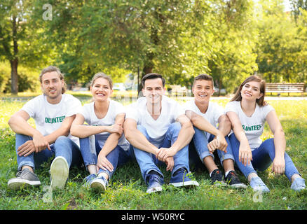 Gruppo di volontari seduti sul prato verde all'aperto Foto Stock