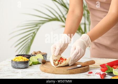 Donna preparando gustosi tacos fresco in cucina Foto Stock