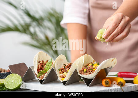 Donna preparando gustosi tacos fresco in cucina Foto Stock