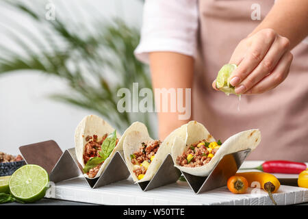 Donna preparando gustosi tacos fresco in cucina Foto Stock