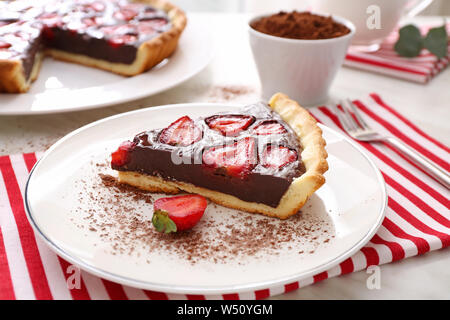 Piastra con il pezzo di gustoso cioccolato torta di fragole su tavola Foto Stock