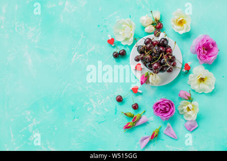Layout creativo realizzato con molla ciliegio fiori di fioritura, vuoto notepad, amaretti e la tazza di caffè in bianco sullo sfondo di legno. Foto Stock