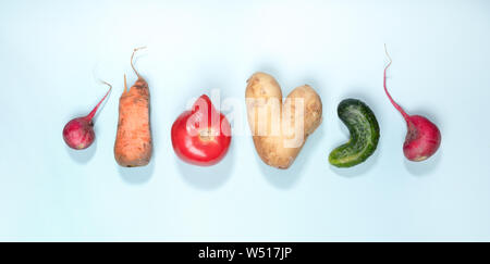 Sei mature brutto ortaggi: patate, pomodori, cetrioli e ravanelli disposti in fila su fondo azzurro. Foto Stock