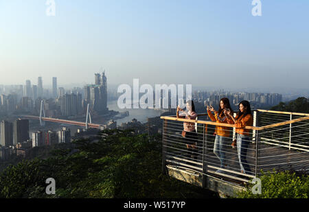 (190726) -- CHONGQING, luglio 26, 2019 (Xinhua) -- i turisti scattare foto di panorami della città in corrispondenza di una piattaforma di osservazione nel sud-ovest della Cina di Chongqing, Ottobre 10, 2018. Situato nel sud-ovest della Cina, Chongqing è l'unico comune in centrale e occidentale in Cina. Costruito sulla montagna e parzialmente circondato da il Yangtze e fiumi Jialing, è noto come un 'Monte città' e una 'città sui fiumi". Essa serve come un importante centro economico e culturale in Cina occidentale. Con le sue particolari caratteristiche topografiche, Chongqing ha lo scenario unico di montagne, fiumi e foreste, sorgenti, cascate, gole e cav Foto Stock