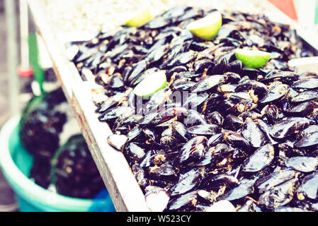 Piatti a base di frutti di mare freschi di cozze con calce per la vendita nel mercato del pesce Pescheria di Catania, Sicilia, Italia Foto Stock