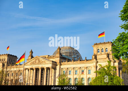 L'edificio del Reichstag di Berlino in Germania con la bandiera tedesca. Un famoso punto di riferimento e meta di viaggio per i turisti Foto Stock