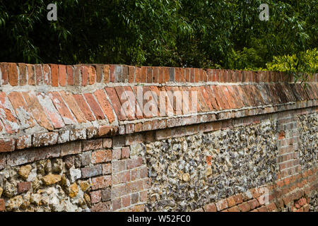 Un tradizionale in mattoni e pietra focaia parete con coperture decorative nel villaggio di South Stoke, Oxfordshire Foto Stock