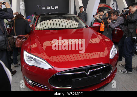 --FILE--persone guardano o scattare delle foto di un modello di Tesla S auto elettrica erogata al suo proprietario al centro vendita di Tesla in Jinqiao, Shanghai, Cina Foto Stock