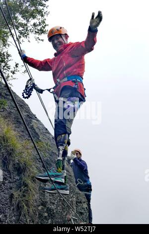 Il 69-anno-vecchio a doppio amputato scalatore cinese Xia Boyu tenta scalata su roccia a una scogliera montagna nella città di Taizhou, est della Cina di provincia dello Zhejiang, 14 Januar Foto Stock