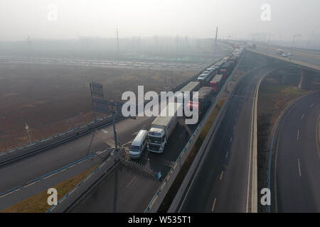 Le vetture si muovono lentamente su una superstrada in pesanti smog e nebbia nella Città di Zhengzhou, centrale cinese della provincia di Henan, 12 gennaio 2019. Foto Stock