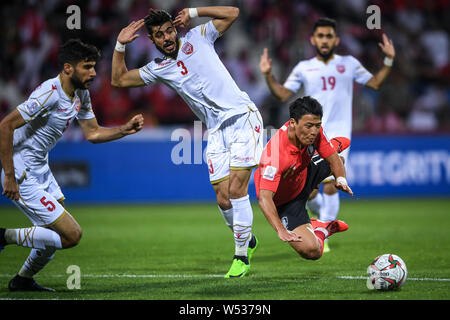 Hwang Hee-chan della Corea del Sud, a destra, cade a terra come egli dribbling contro il Bahrain nel giro di 16 Corrispondenza tra la Corea del Sud e il Bahrain duri Foto Stock