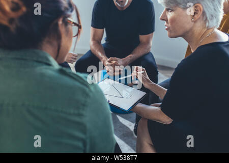 Coppia business donna che spiega la strategia per la squadra nel corso di una riunione. Multi-etnico gruppo di persone sedute aventi insieme un incontro. Foto Stock