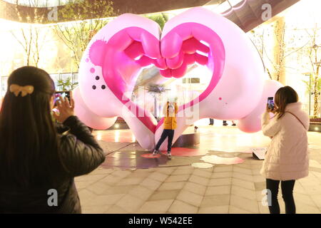 I pedoni rappresentano per le foto con una coppia di gigante cartoon mani formando un cuore a Xintiandi Square in Cina a Shanghai, 28 gennaio 2019. Una coppia di gi Foto Stock