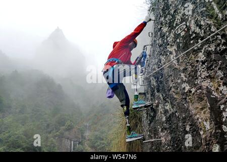 Il 69-anno-vecchio a doppio amputato scalatore cinese Xia Boyu tenta scalata su roccia a una scogliera montagna nella città di Taizhou, est della Cina di provincia dello Zhejiang, 14 Januar Foto Stock