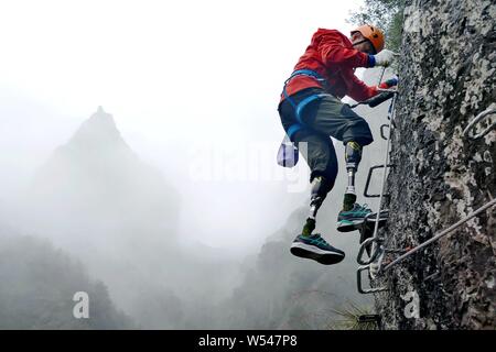 Il 69-anno-vecchio a doppio amputato scalatore cinese Xia Boyu tenta scalata su roccia a una scogliera montagna nella città di Taizhou, est della Cina di provincia dello Zhejiang, 14 Januar Foto Stock