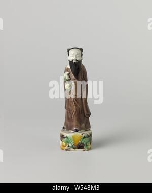 La figura di un uomo barbuto tenendo un fiore, immagine di un uomo su un piedistallo di porcellana dipinta su biscotti in verde, giallo, la melanzana e il nero. L'immagine mostra una permanente uomo barbuto con un fiore nella sua mano destra. Un chip nella base. Email sur biscotto., anonimo, Cina, c. 1700 - c. 1724, Qing-dinastia (1644-1912) / Kangxi-periodo (1662-1722) / Yongzheng-periodo (1723-1735), porcellana (materiale), smalto, vetrificazione, h 12.8 cm l 3,9 cm × w 2,9 cm Foto Stock