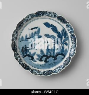 Piattino-piatto con figure in un paesaggio con un padiglione e alberi, pirofila con parete nervata e il rinforzo a forma di cerchio, dipinta in underglaze blu. Sul ripiano di una società in un paesaggio. Tre persone accanto a piante di banana tra piante, due persone in più sulla sinistra. Sullo sfondo di un padiglione con un banner tra gli alberi. La parete è suddivisa in caselle semicircolare riempiti con viticci. La parete esterna con un continuo lotus vine. Contrassegnato sulla parte inferiore con il sei-marchio di caratteri dell'Imperatore Chenghua. Tre proen sul fondo. Arita, blu e bianco., anonimo, Giappone, c. 1700 - c. 1799 Foto Stock