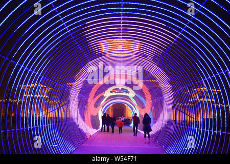 I visitatori a piedi attraverso un tunnel illuminato da luci colorate, che è chiamato 'tunnel temporale light show", in Xiangyang city, centrale della Cina di Hubei prov Foto Stock