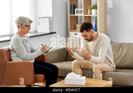 Senior donna psicologo e triste uomo paziente Foto Stock