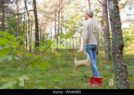 Giovane donna la raccolta di funghi nella foresta di autunno Foto Stock