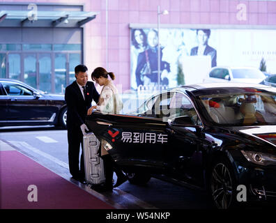 --FILE--un cliente scende da un veicolo con il logo di autonoleggio service provider Yongche Yidao presso un hotel a Pechino, in Cina, il 26 dicembre 2018. A- Foto Stock