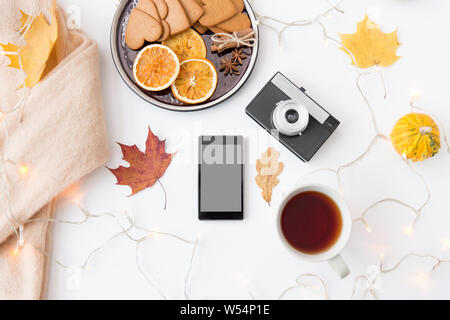 Smartphone, tè, fotocamera, cookie e foglie di autunno Foto Stock