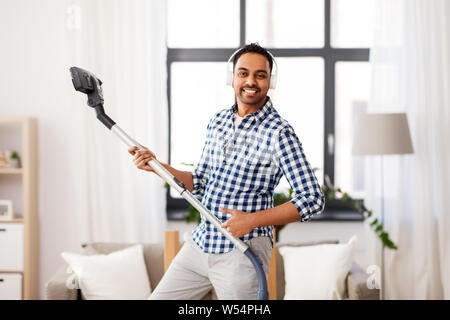 Uomo in cuffie con aspirapolvere a casa Foto Stock