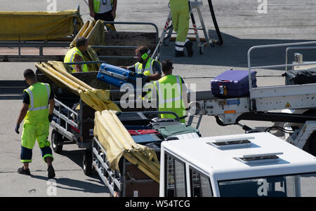 Berlino, Germania. 26 Luglio, 2019. Personale a terra dell'aeroporto di Schoenefeld pack valigie e borse da un aereo è atterrato su un carrello di trasporto. Credito: Paolo Zinken/dpa/Alamy Live News Foto Stock