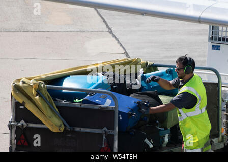 Berlino, Germania. 26 Luglio, 2019. Un dipendente del personale di terra dell'aeroporto di Schoenefeld pack valigie e borse da un aereo è atterrato su un carrello. Credito: Paolo Zinken/dpa/Alamy Live News Foto Stock