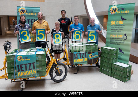 Stuttgart, Germania. 26 Luglio, 2019. I sostenitori di una petizione per un referendum sulla protezione delle specie sono in piedi nel foyer del Ministero dell'interno del Baden-Württemberg con forme firmato da decine di migliaia di persone. Gli iniziatori ha presentato una domanda di riconoscimento per il referendum salva le api' per il Baden-Württemberg Ministero dell'Interno. Credito: Linda Vogt/dpa/Alamy Live News Foto Stock