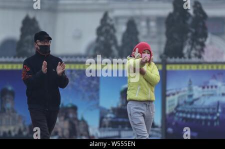 I residenti locali che indossano maschere viso contro l' inquinamento atmosferico fare esercizi di smog pesante nella città di Harbin, a nord-est della Cina di Provincia di Heilongjiang, 27 Februa Foto Stock