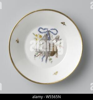 Piattino appartenente a un set per il tè con decorazione di trofei su nastri, set da tè costituito da una teiera, una tazza di zucchero, un lavandino e dodici tazzine e piattini variopinti con trofei appesi sulle centine blu. I Trofei si riferiscono alle varie professioni. Contrassegnate in nero: Amstel (il Sugar Bowl Amstel N. 805 e inciso A). Diversi segni incisi nelle tazze e piattini., Koninklijke Porseleinfabriek Dommer & Co., Nieuwer-Amstel, 1809 - in o prima di 1814, porcellana (materiale), h 2,4 cm × d 13,2 cm Foto Stock