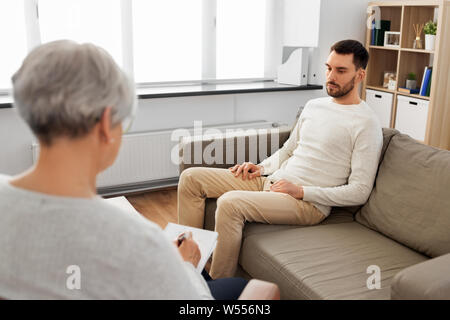 Senior donna psicologo e triste uomo paziente Foto Stock