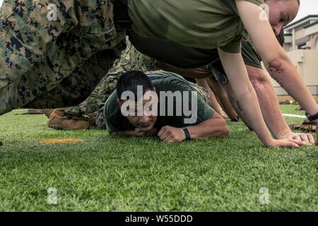 Stati Uniti GySgt Marini, 26 luglio 2019. Juan Flores, con sede e Sede Squadron, conduce il crawl bassa durante un squadrone di allenamento fisico evento al Marine Corps Air Station Iwakuni, Giappone, 26 luglio 2019. HandHS supporta i comandi di tenant a MCAS Iwakuni attraverso il controllo del traffico aereo, aeromobili di salvataggio e di lotta antincendio e di combustibili a lungo con molte altre funzionalità. Unità regolari di formazione fisica di eventi come questo aiutano a mantenere la disponibilità, il morale e la coesione dell'unità. (U.S. Marine Corps photo by Lance Cpl. Lauren Brune). () Foto Stock