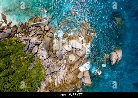 Vista aerea di una piccola baia su una splendida isola tropicale con barriera corallina e massi di granito Foto Stock