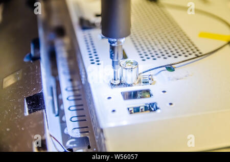 L'uomo unspins il coperchio del computer del monoblocco con un cacciavite con retroilluminazione Foto Stock