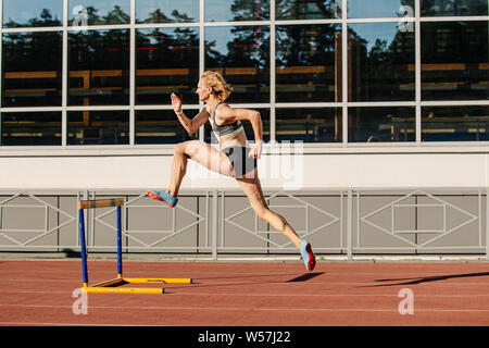 Atleta femminile correre i 400 metri a ostacoli di atletica leggera a Stadium Foto Stock