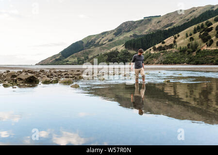 Uomo che cammina in estuario a bassa marea Foto Stock