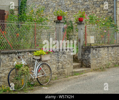 Feneyrols, Midi Pirenei, Francia - Luglio 23, 2017: bicicletta decorativo con fiori in appoggio su una rustica facciata del villaggio Foto Stock