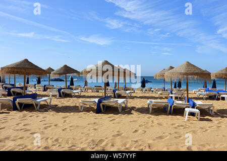 La paglia di ombrelloni e sedie a sdraio sulla spiaggia di Albufeira Foto Stock