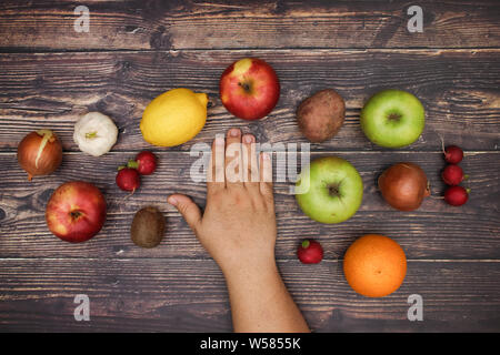 Mano d'uomo e frutta fresca intorno a un tavolo di legno Foto Stock