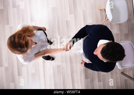 Vista laterale di happy businessman stringe la mano con il suo partner in ufficio Foto Stock