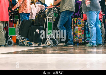 I passeggeri in attesa in linea per l'imbarco di un aeroporto per un volo, viaggiatori coda al momento del check-in, di ritorno dalle vacanze per il peggiore dei giorni, aria congestionate Foto Stock