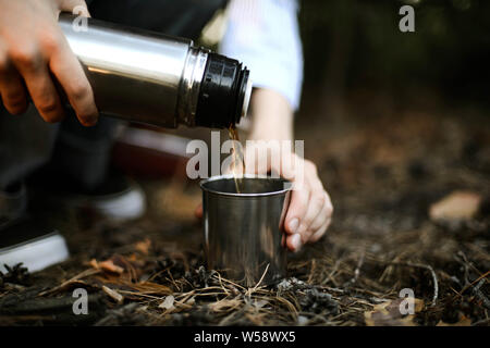 Close-up di donna versando il tè isolato dal contenitore per bevande int Foto Stock
