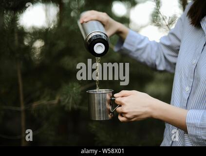 Close-up di donna versando il tè isolato dal contenitore per bevande int Foto Stock