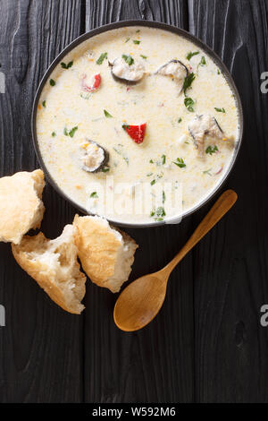 Cremosa zuppa di pesce con anguille, formaggio e verdure close-up in una ciotola sul tavolo. Verticale in alto vista da sopra Foto Stock