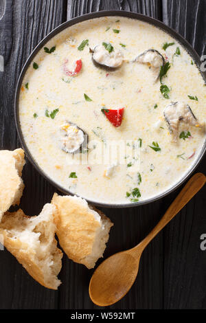 Deliziosa cremosa zuppa di pesce con anguille, formaggio e verdure close-up in una ciotola sul tavolo. Verticale in alto vista da sopra Foto Stock